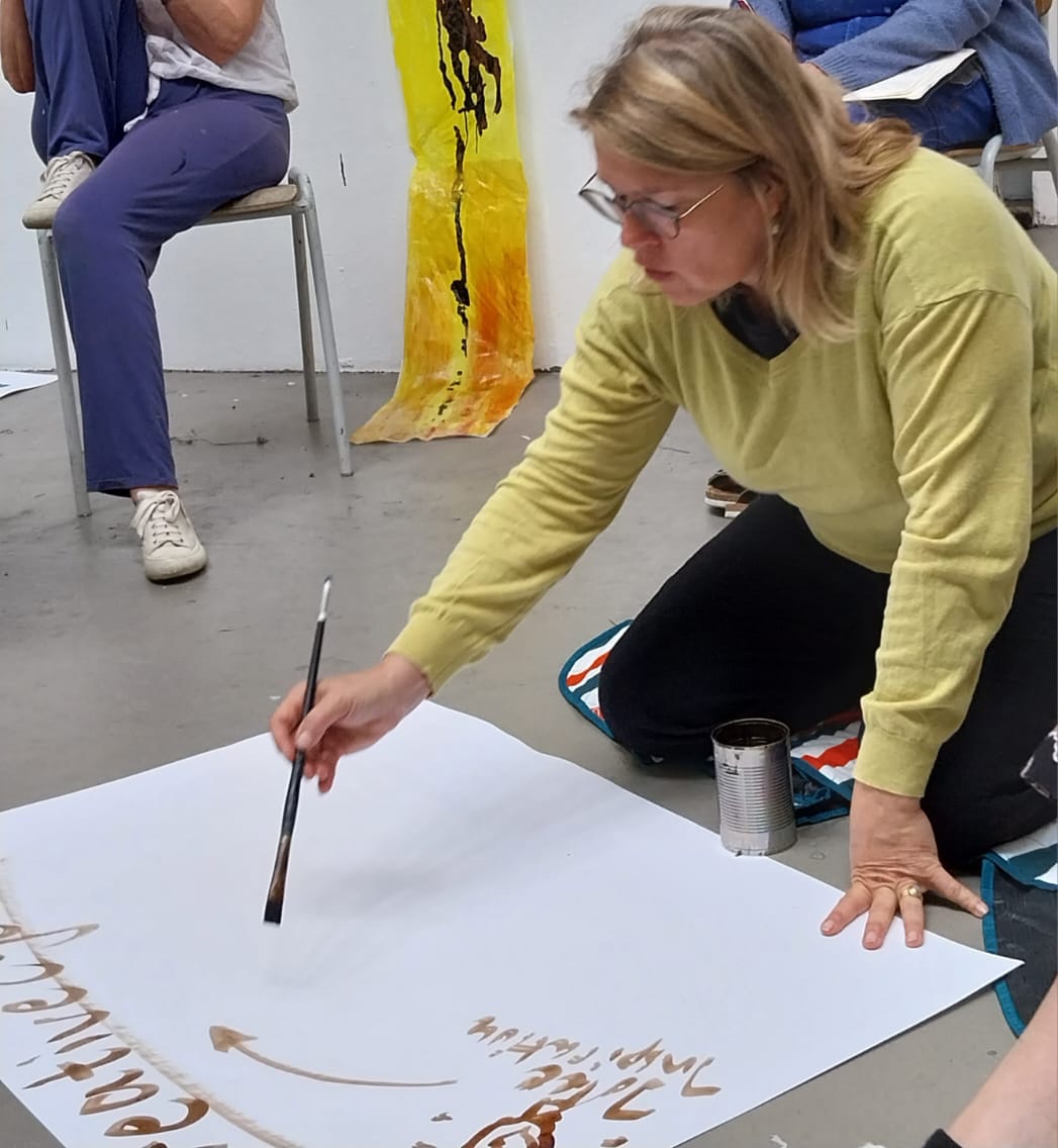Angelika Kehlenbach malt mit Pinsel auf großem Papier am Boden